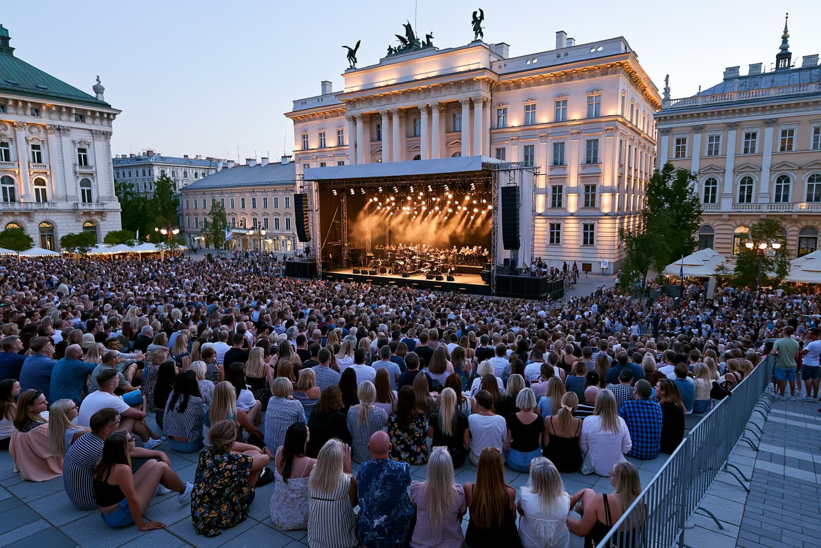 Gomila se okuplja u sumrak na povijesnom berlinskom trgu gdje je pozornica za orkestar na otvorenom osvijetljena uz veličanstvene fasade.