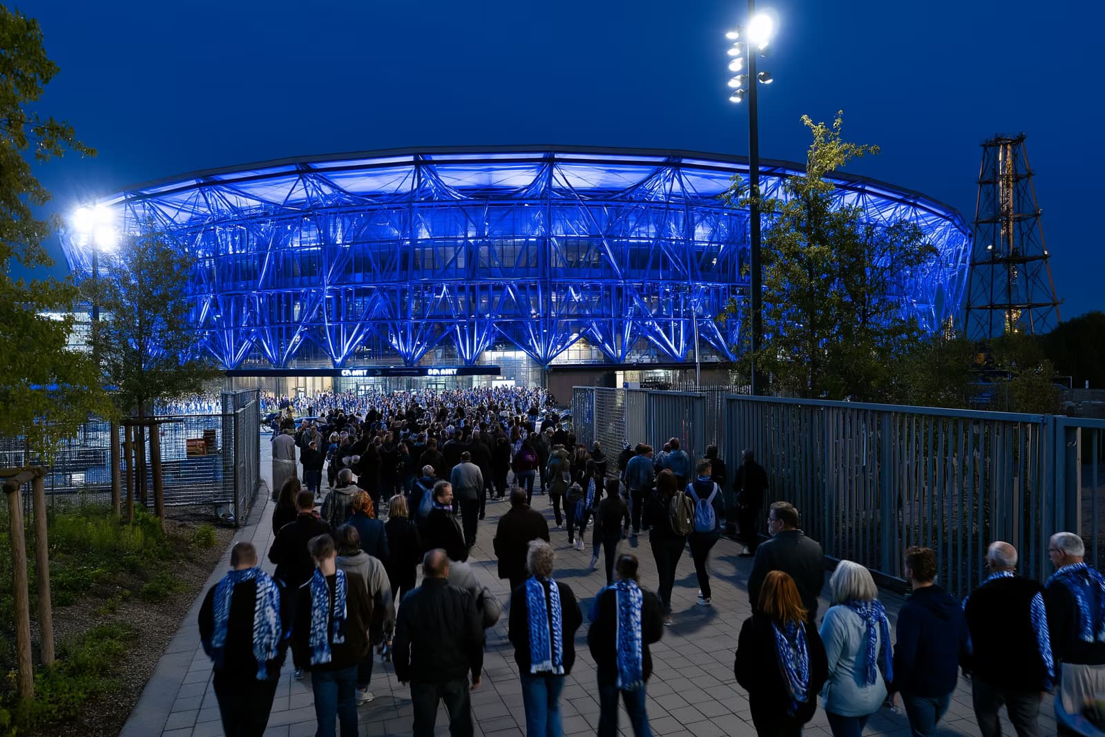 Nogometni stadion u Ruhru noću svijetli kraljevsko plavom bojom dok navijači u šalovima hrle prema vratima nakon transfera Gosensa u Schalke.